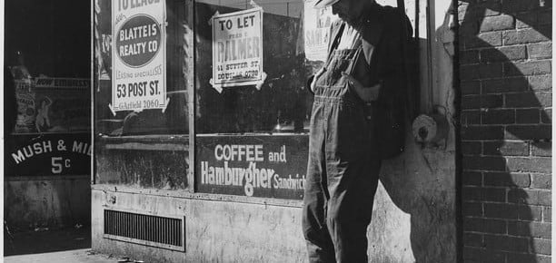 Unemployed,destitute man leaning against vacant store-photo by Dorothea Lange